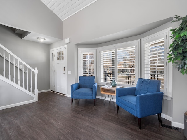 sitting room with stairway, wood finished floors, baseboards, visible vents, and lofted ceiling