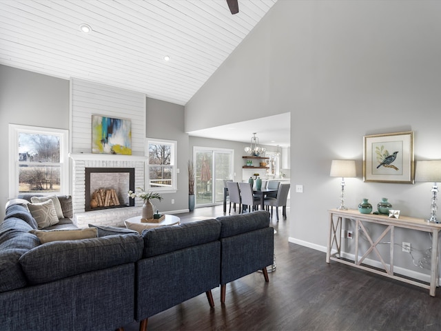 living area featuring dark wood-style floors, a fireplace, high vaulted ceiling, and baseboards