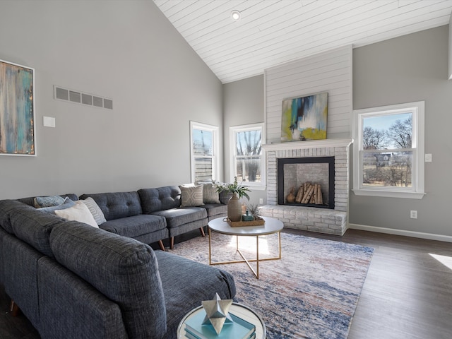 living area with wood finished floors, visible vents, baseboards, high vaulted ceiling, and a fireplace