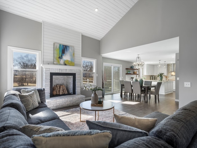 living area with a fireplace, wooden ceiling, wood finished floors, a notable chandelier, and high vaulted ceiling