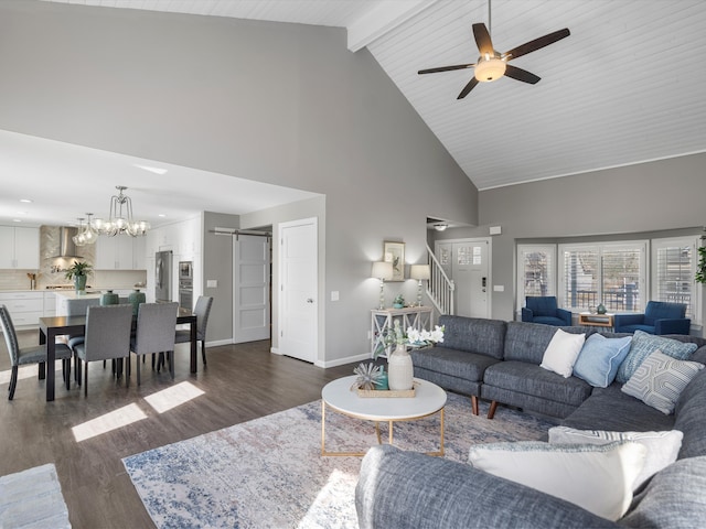 living area with stairs, a barn door, beam ceiling, ceiling fan with notable chandelier, and dark wood-style floors