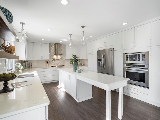 kitchen featuring a sink, dark wood finished floors, stainless steel appliances, wall chimney exhaust hood, and decorative backsplash