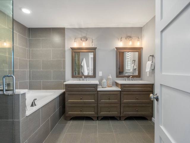 full bathroom with double vanity, a bath, tile patterned flooring, and a sink