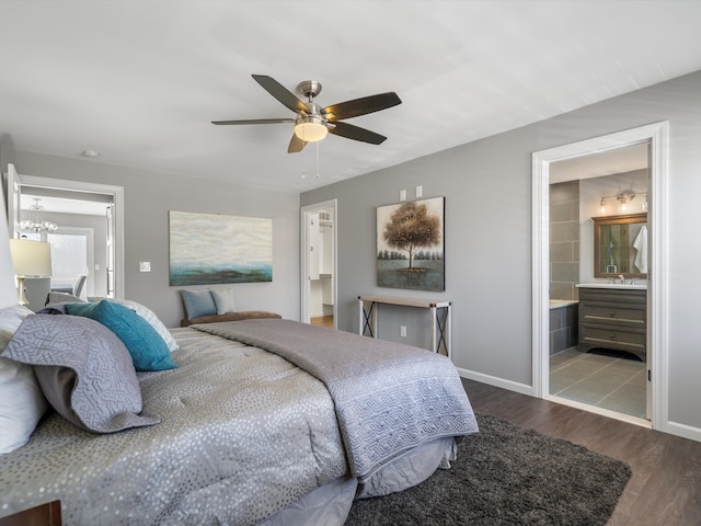 bedroom featuring baseboards, wood finished floors, ensuite bathroom, and ceiling fan with notable chandelier