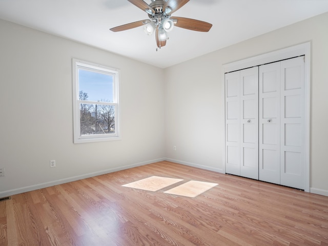 unfurnished bedroom with a closet, baseboards, light wood-style floors, and ceiling fan