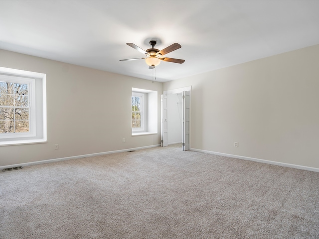 empty room featuring visible vents, baseboards, light colored carpet, and a ceiling fan