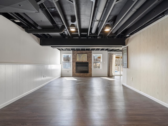 unfurnished living room featuring dark wood-style floors, beamed ceiling, a fireplace, and baseboards