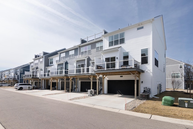 exterior space with central air condition unit, a residential view, concrete driveway, and an attached garage