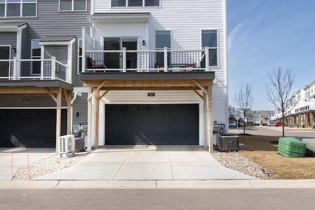 view of front of property featuring cooling unit, a residential view, concrete driveway, a garage, and a balcony