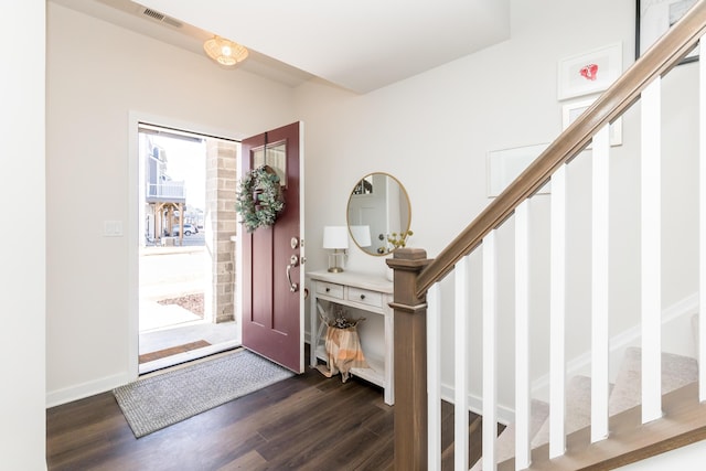 foyer featuring stairway, baseboards, dark wood-type flooring, and visible vents