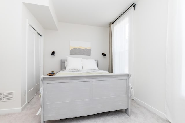 bedroom with light colored carpet, visible vents, a closet, and baseboards