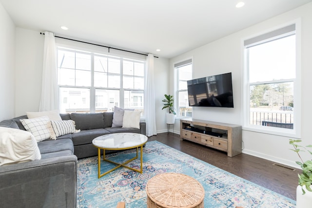 living room featuring visible vents, a healthy amount of sunlight, baseboards, and wood finished floors