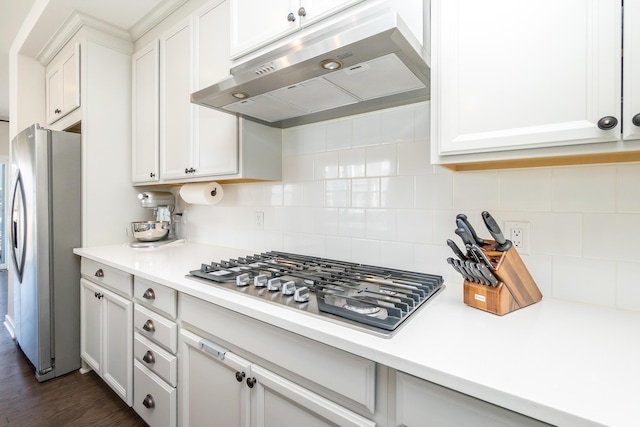 kitchen with light countertops, white cabinets, under cabinet range hood, appliances with stainless steel finishes, and backsplash