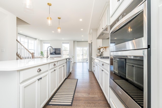 kitchen featuring a sink, stainless steel appliances, wood finished floors, and light countertops