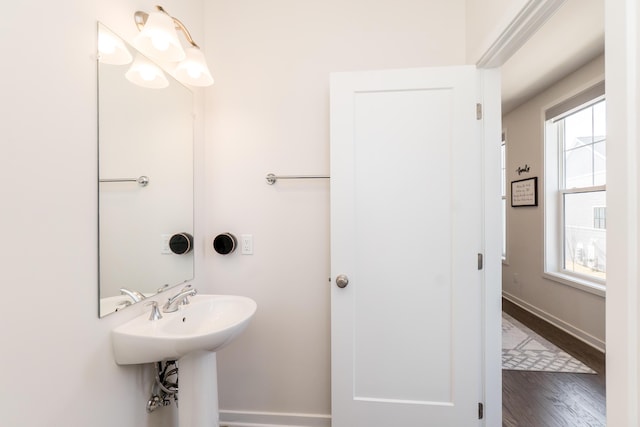 bathroom with a wealth of natural light, baseboards, wood finished floors, and a sink