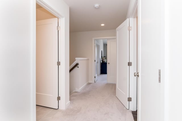 hallway featuring recessed lighting, light colored carpet, baseboards, and an upstairs landing