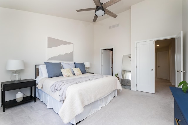 bedroom featuring a high ceiling, a ceiling fan, visible vents, and light carpet