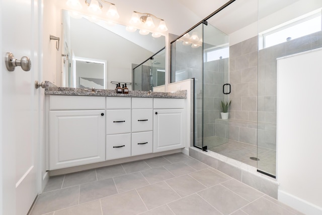 bathroom with tile patterned flooring, a stall shower, and double vanity