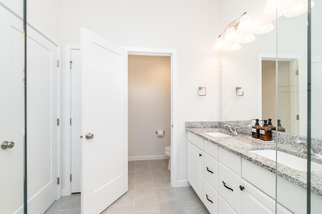 bathroom with tile patterned flooring, double vanity, toilet, and a sink