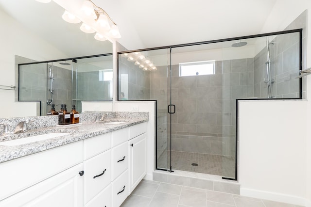 full bathroom featuring tile patterned floors, a stall shower, double vanity, and a sink