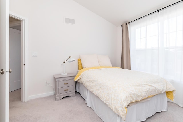 bedroom featuring vaulted ceiling, baseboards, visible vents, and light carpet