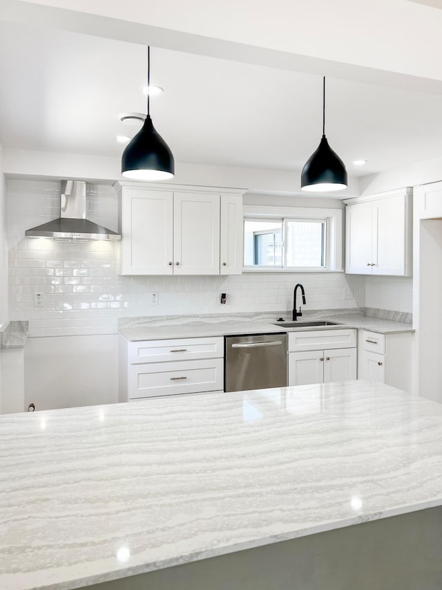 kitchen with stainless steel dishwasher, wall chimney range hood, light stone counters, and a sink