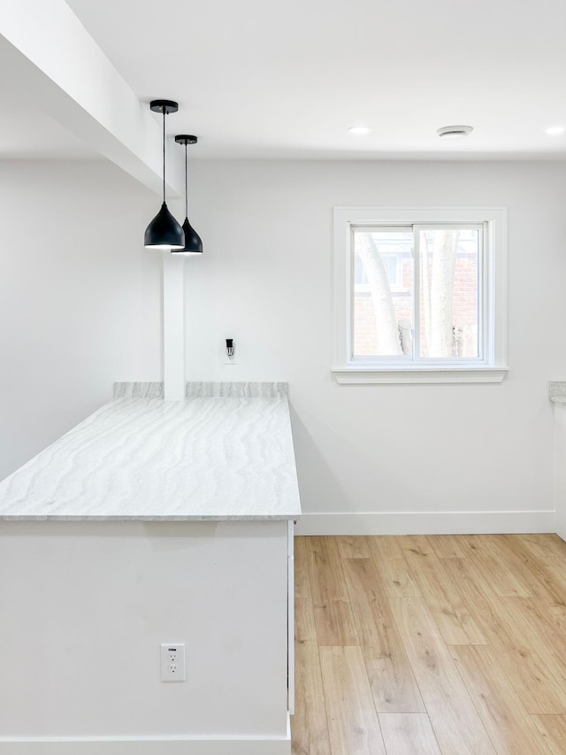 interior space with baseboards, pendant lighting, recessed lighting, light wood-style flooring, and a peninsula