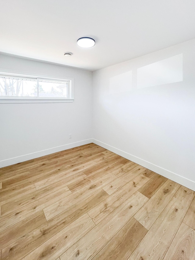 spare room featuring light wood-type flooring and baseboards