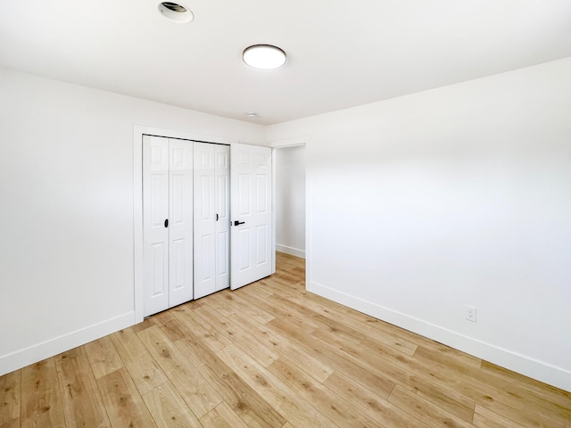 unfurnished bedroom featuring a closet, baseboards, and light wood-style floors