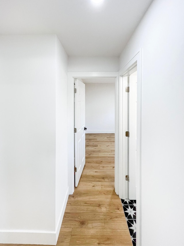 corridor featuring light wood-style floors and baseboards