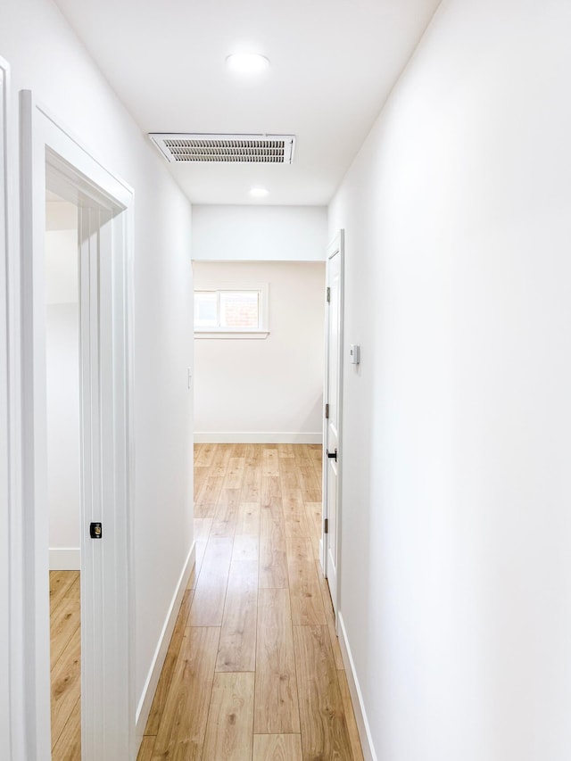 hall with light wood-style floors, visible vents, and baseboards