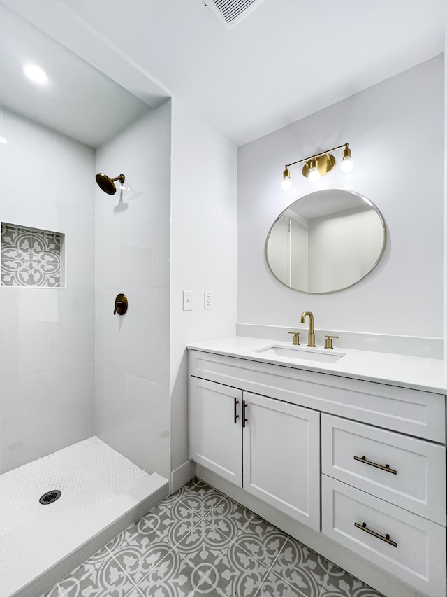 full bath featuring vanity, tile patterned floors, visible vents, and a tile shower