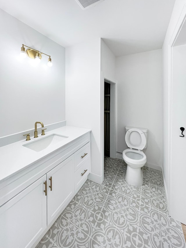 bathroom featuring visible vents, toilet, vanity, and baseboards