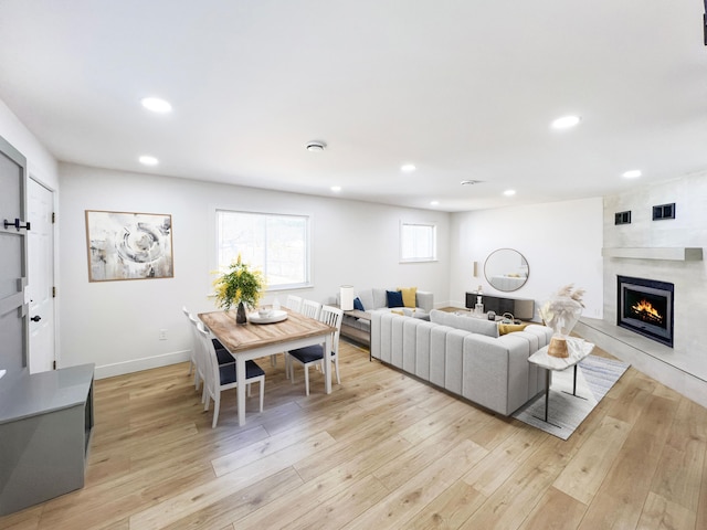 living area with recessed lighting, light wood-style floors, and a high end fireplace