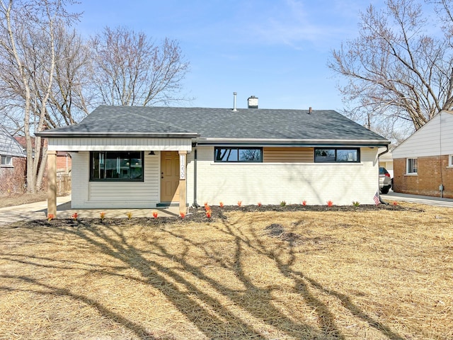 view of front facade with a porch, brick siding, and roof with shingles