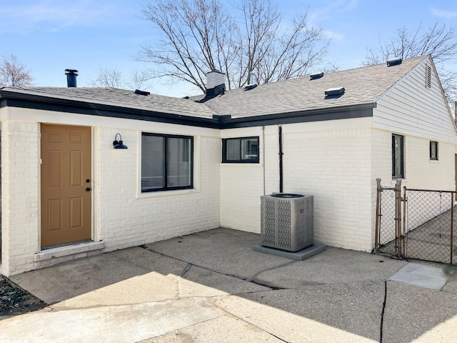 doorway to property featuring a gate, fence, central AC, a patio area, and brick siding