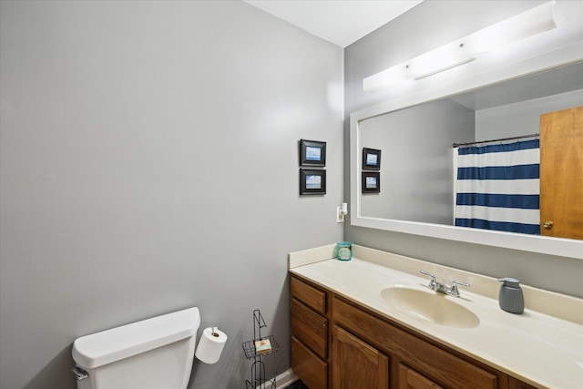 bathroom featuring toilet, vanity, and a shower with curtain