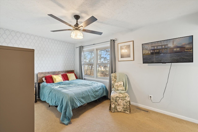 carpeted bedroom with visible vents, a textured ceiling, wallpapered walls, and baseboards