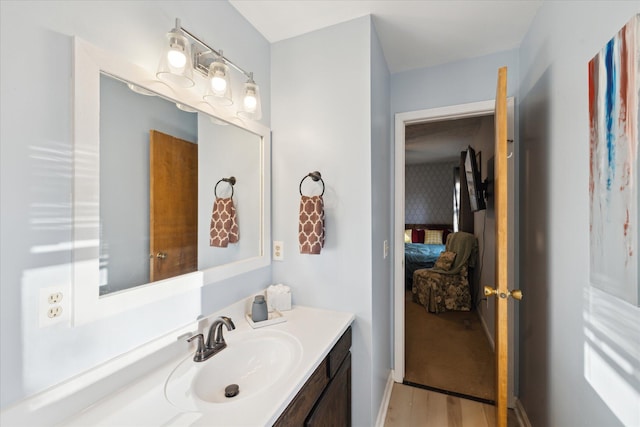 ensuite bathroom with vanity, wood finished floors, and connected bathroom