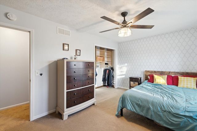 bedroom with visible vents, light carpet, a textured ceiling, wallpapered walls, and baseboards