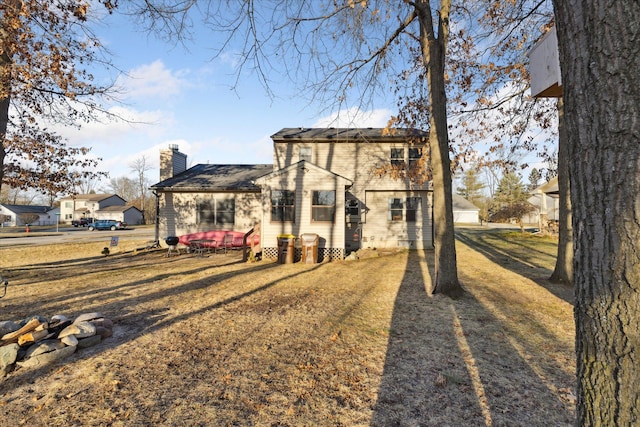 rear view of property with a chimney and a yard