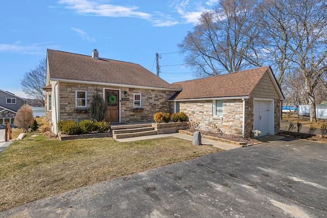 view of front of property with a front yard, driveway, a shingled roof, a garage, and stone siding