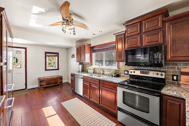 kitchen with a ceiling fan, a sink, dark wood finished floors, appliances with stainless steel finishes, and baseboards