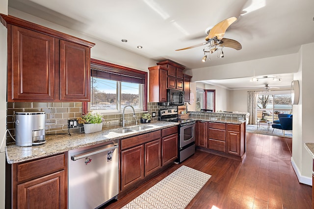 kitchen with dark wood-type flooring, ceiling fan, a peninsula, stainless steel appliances, and a sink