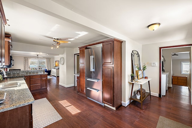 kitchen with a sink, ceiling fan, a peninsula, high end fridge, and dark wood-style flooring