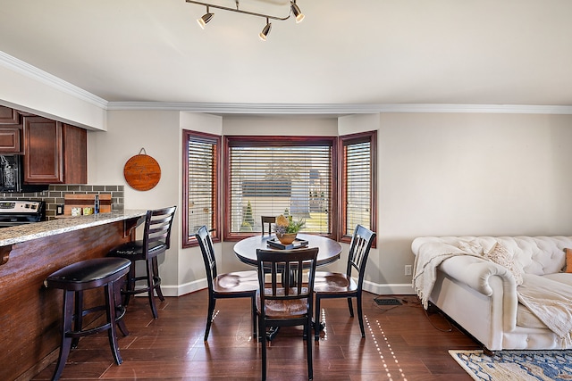 dining room with ornamental molding, baseboards, and dark wood-style flooring