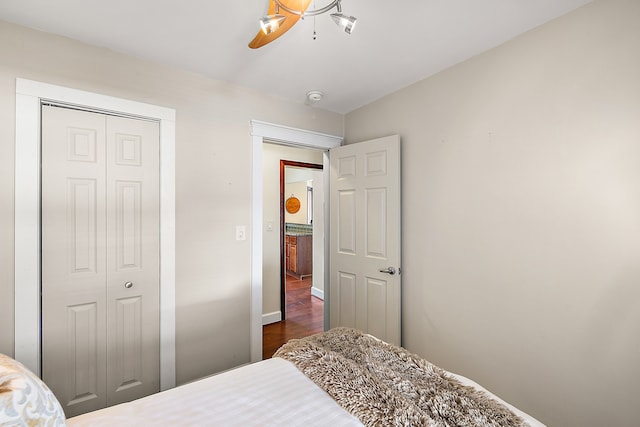 bedroom featuring a closet, baseboards, dark wood-type flooring, and ceiling fan