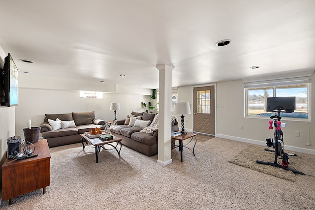 living room featuring decorative columns, baseboards, a healthy amount of sunlight, and carpet flooring