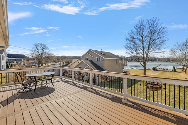 wooden terrace featuring a yard, a water view, and outdoor dining area