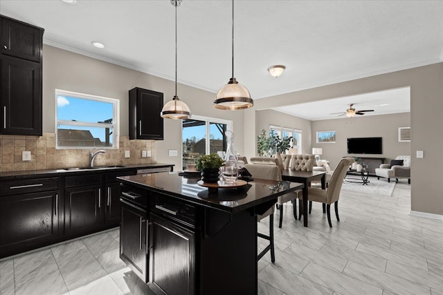 kitchen featuring tasteful backsplash, dark countertops, dark cabinetry, and a sink